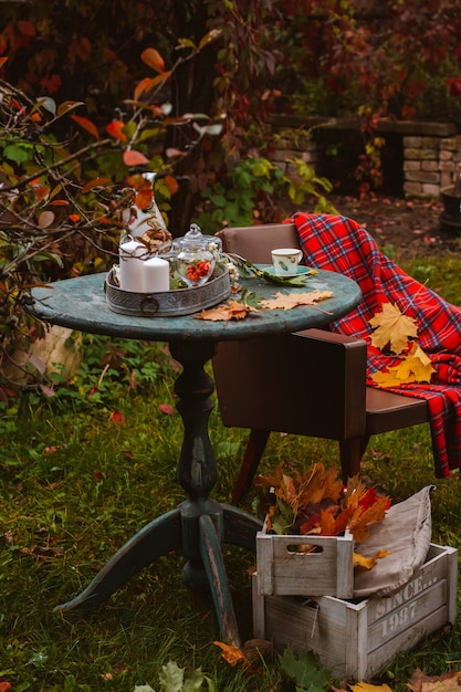 Gezellige patio. De herfstbladeren liggen houten antieke rondetafel met de koekjes van aardewerkkoppen