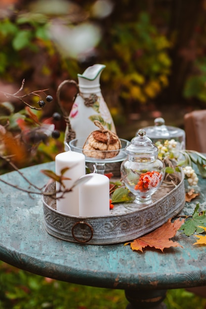 Gezellige patio. De herfstbladeren liggen houten antieke rondetafel met de koekjes van aardewerkkoppen