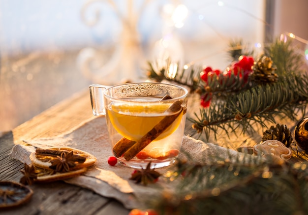 Gezellige scène voor open haard en kerstboom versierd speelgoed en kerstverlichting met kopjes thee op houten tafel, in landhuis, wintervakantie van kerstavond.