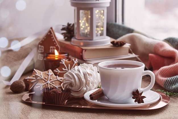 Gezellige winterse sfeer op de vensterbank Esthetisch kerstraam met boeken peperkoekkoekjes marshmallow kopje espresso kaars gezellige achtergrond