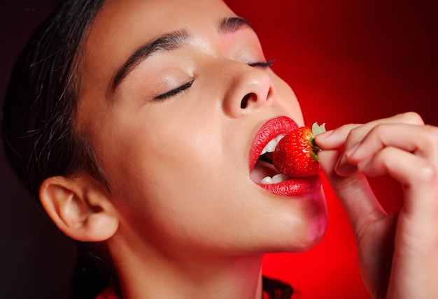 Gezicht eten en vrouw met rode aardbei voor fruit detox gezondheid wellness doelen of voedingsdeskundige dieet Lippenstift make-up erotische schoonheid en sexy model meisje met voedingsproduct huidverzorging en cosmetica