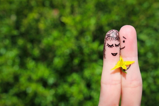 Gezicht geschilderd op vingers. De man geeft bloemen aan een vrouw.