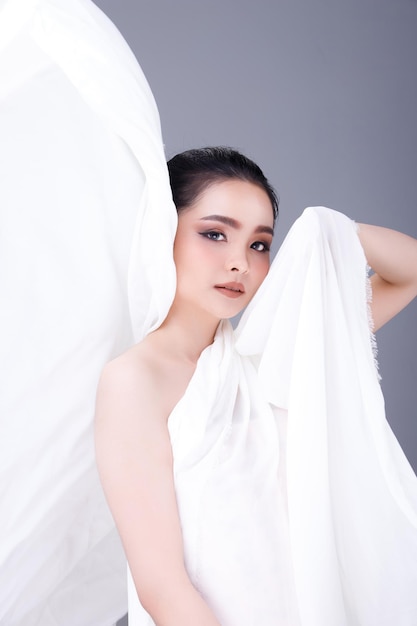 Gezicht geschoten Portret van Fashion 20s Aziatische vrouw mooi zwart haar express gevoel sensuele gelukkige glimlach. Meisje houdt paarse orchideebloem vast voor cosmetische huidverzorging en behandeling over roze achtergrond