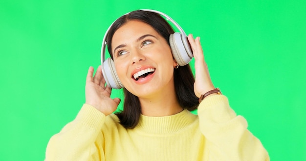Gezicht groen scherm en vrouw met koptelefoon dansen en muziek streamen tegen de achtergrond van een studio Portret vrouw en persoon met koptelefoon luisteren naar audio en geluiden voor beweging en glimlach