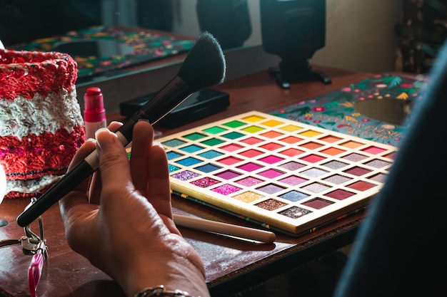 Gezicht op de arm van een meisje met een make-upborstel in haar hand voor haar bruine houten kaptafel