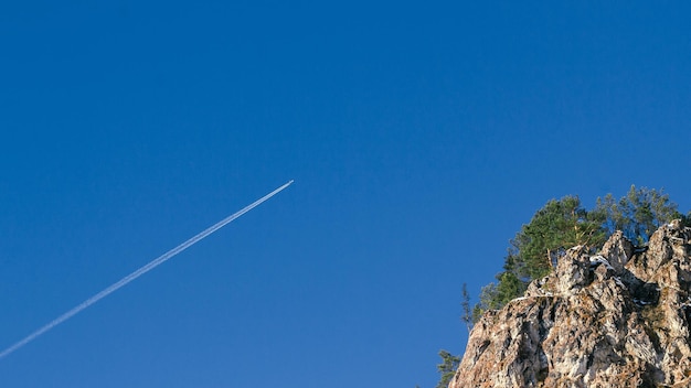 Gezicht op een vliegend vliegtuig tegen de achtergrond van de lucht en de rotsen