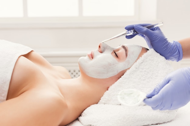 Gezicht peeling masker, spa schoonheidsbehandeling, huidverzorging. vrouw, krijgen, gezichtsverzorging, door, schoonheidsspecialiste, op, spa salon, zijaanzicht, close-up