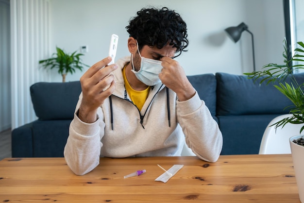 Foto gezicht van een ongelukkige volwassen man met een positief testapparaat voor covid19 verdrietig persoon