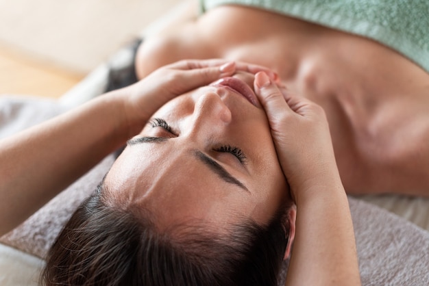 Foto gezicht van het meisje close-up de massagetherapeut maakt massage groene achtergrond