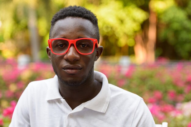 Gezicht van jonge Afrikaanse man met bril in het park buitenshuis