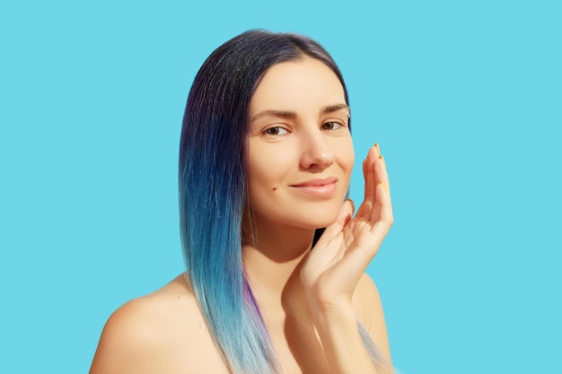 Gezicht van jonge mooie vrouw met blauw haar op lichte achtergrond Schoonheidssalon behandeling concept