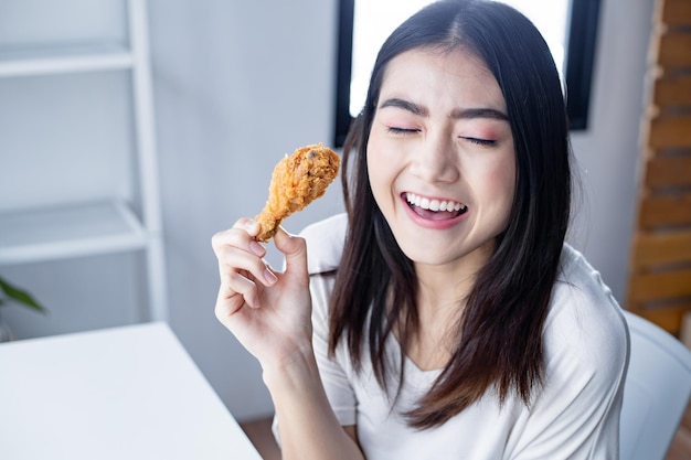 Gezicht van jonge vrouw was blij om de heerlijke gebakken kip te eten. gebakken kip drumstick