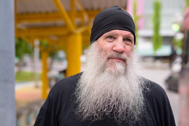 Gezicht van volwassen knappe bebaarde hipster man te wachten bij de bushalte