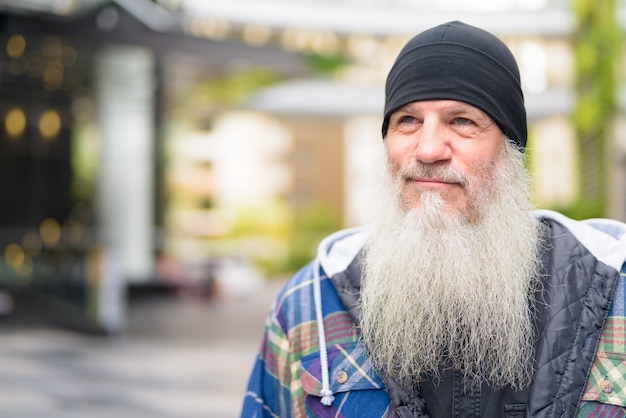 Gezicht van volwassen knappe bebaarde man denken in de stad