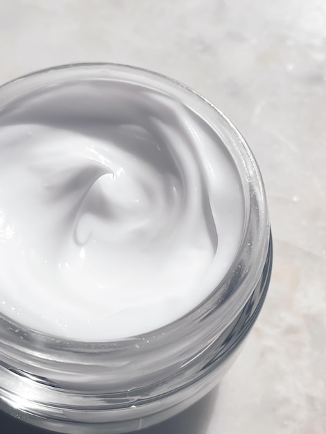 Gezichtscrème moisturizer glazen pot op marmeren steen achtergrond huidverzorging en cosmetisch schoonheidsproduct concept