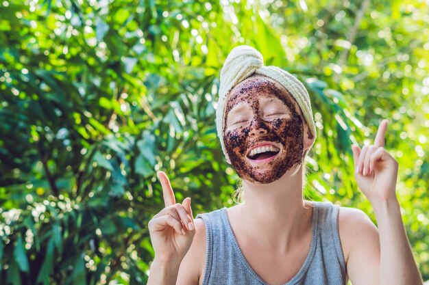 Gezichtshuid scrub portret van sexy glimlachend vrouwelijk model dat natuurlijke koffiemasker toepast gezichtsscrub op