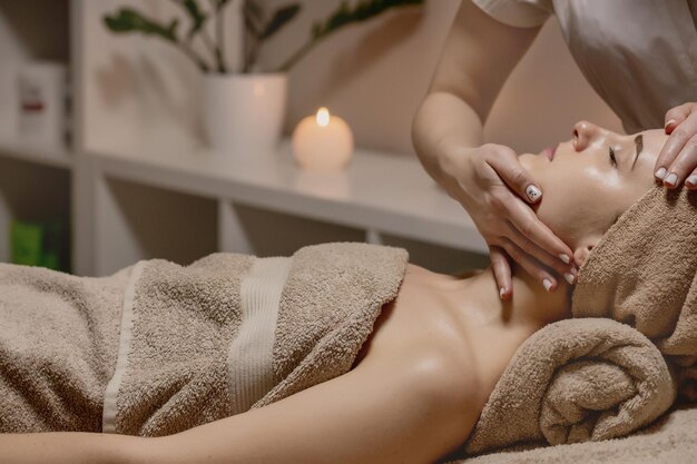 Gezichtsmassage Close-up van een jonge vrouw die een spa-massagebehandeling krijgt bij een schoonheidssalon Spa huid- en lichaamsverzorging Gezichtsschoonheidsbehandeling Cosmetologie