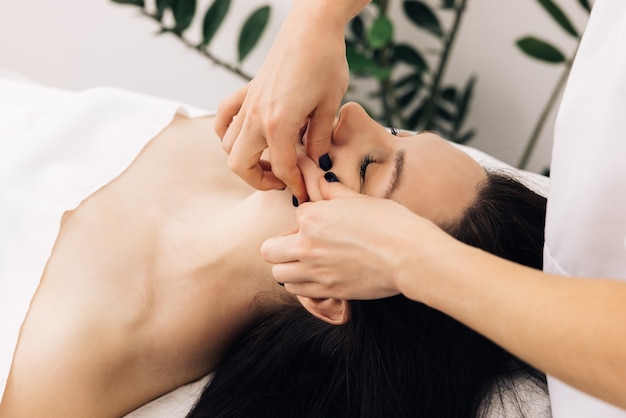 gezichtsmassage in beauty spa salon vrouw genieten van ontspannende gezichtsmassage in cosmetology spa center