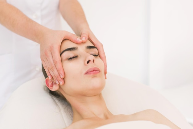 Gezichtsmassage mooi meisje. Portret van een meisje in een massagesalon. Schoonheidsspecialiste die massage van vrouwelijke gezichten doet. Massage gezicht meisje close-up.