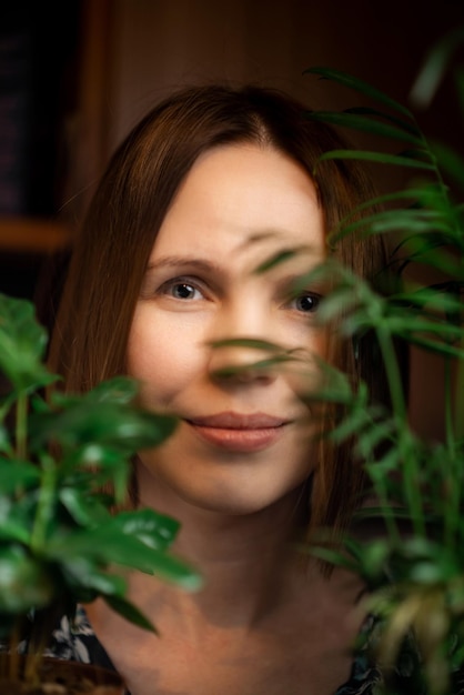 Gezichtsportret van een vrouw van middelbare leeftijd in groene planten glimlachend Een vrouw van in de veertig Ontspanning kalm staat blij gezicht