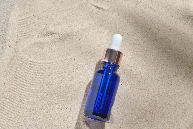 Gezichtsserum van glazen fles met een pipet op een natuurlijke achtergrond met zand Etherische olie voor het hydrateren van de lichaamshuid mockup van schoonheidsmode cosmetisch flesdruppelproduct met huidverzorgingsconcept