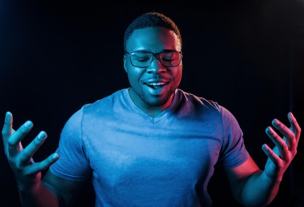 Gezichtsuitdrukking Futuristische neonverlichting Jonge Afro-Amerikaanse man in de studio