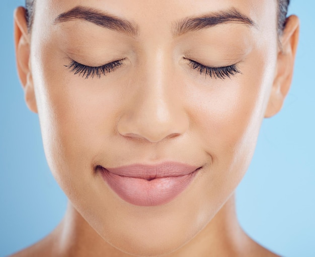 Gezichtsvrouw en make-up in studio voor schoonheid, huidverzorging en verzorging tegen een blauwe achtergrondruimte Glamour headshot en meisjesmodel ontspannen in luxe cosmetische huid en natuurlijke wellness en behandeling