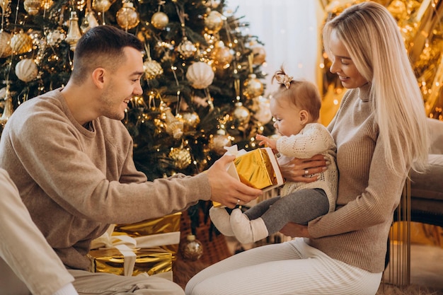 Gezin met dochtertje met kerstcadeau onder de boom