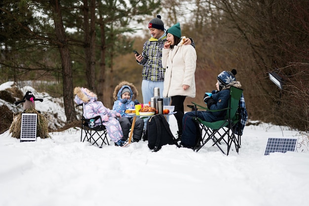 Gezin met drie kinderen in het winterbos die samen tijd doorbrengen op een picknick