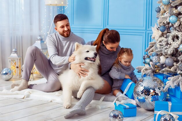 Gezin met hond en dochter brengen samen tijd door terwijl ze in de buurt van de kerstboom in de woonkamer zitten