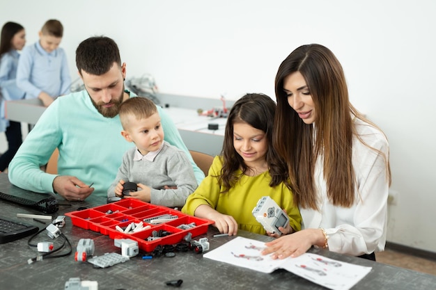 Gezin met kinderen in een robotclub maakt een robot bestuurd door een constructeur