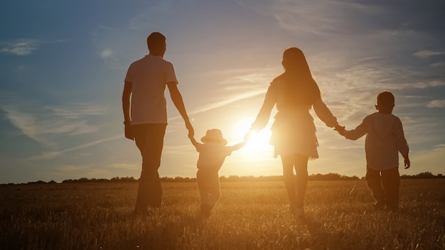 Foto gezin met kinderen loopt langs velden bij ondergaande zon