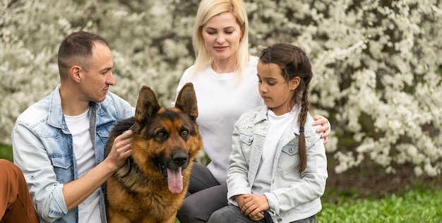 Gezin met kleine dochter en hond buiten wandelen in de boomgaard in het voorjaar