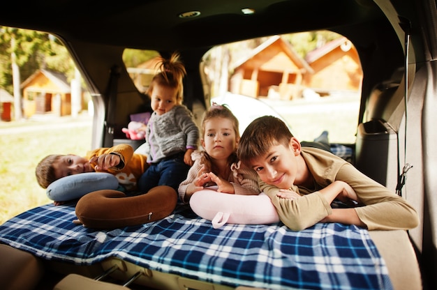 Gezin van vier kinderen in het interieur van het voertuig. Kinderen in de kofferbak. Reizen met de auto, liegen en plezier maken, sfeerconcept.