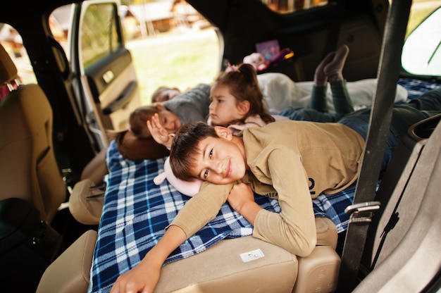 Gezin van vier kinderen in het interieur van het voertuig. Kinderen in de kofferbak. Reizen met de auto, liegen en plezier maken, sfeerconcept.