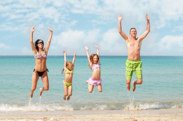 Gezin van vier springen op het strand