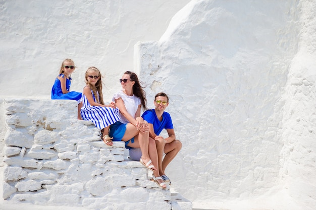 Gezinsvakantie in europa. ouders en kinderen op straat van typisch grieks traditioneel dorp met witte muren en kleurrijke deuren op het eiland mykonos, in griekenland