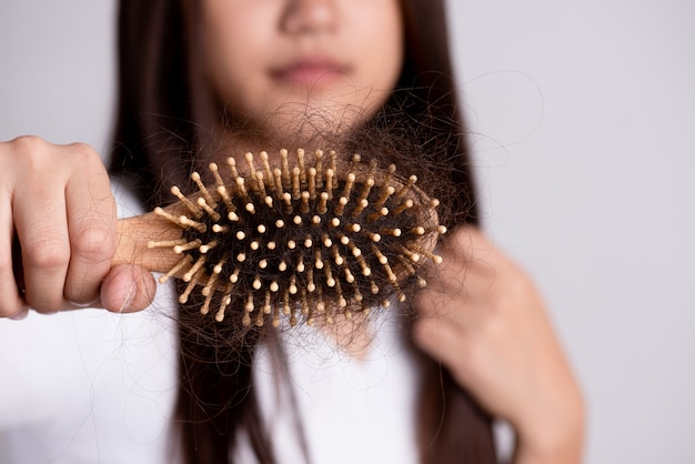 Gezond concept. De vrouw toont haar borstel met beschadigd haar met lang verlies