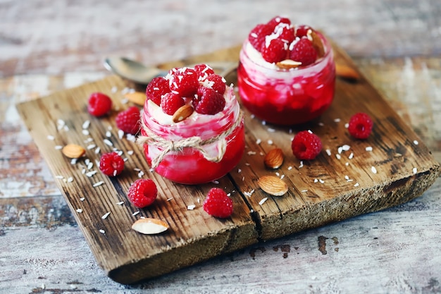 Gezond dessert in potten met gestremde melkroom en frambozen.