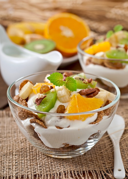 Gezond dessert met muesli en fruit in een glazen kom op tafel