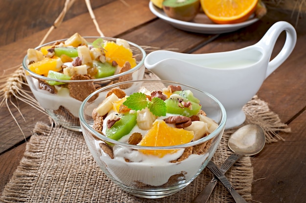 Gezond dessert met muesli en fruit in een glazen kom op tafel