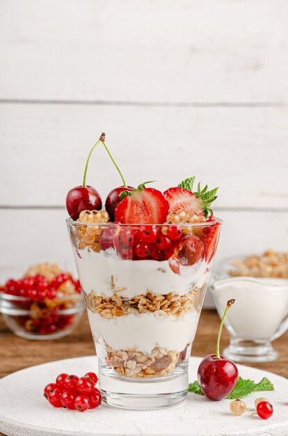 Gezond dessert van muesli met yoghurt en verse bessen op witte houten muur