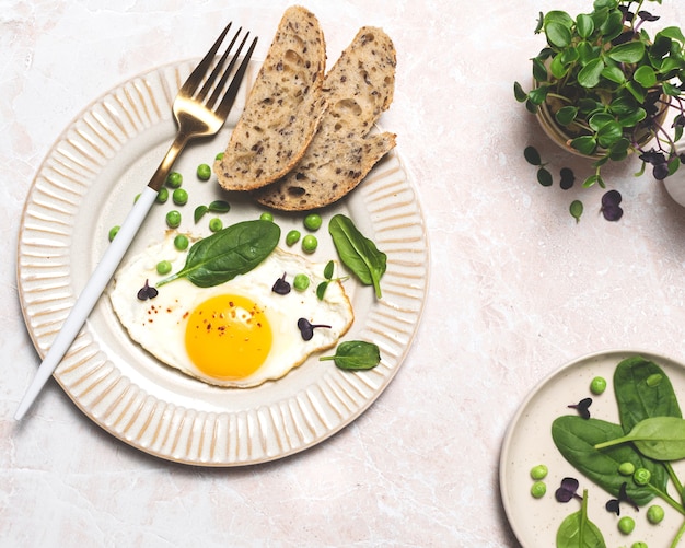 Foto gezond eierontbijt met spinazie en microgreens, bovenaanzicht op marmeren tafel