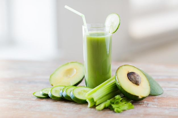gezond eten, biologisch voedsel en dieetconcept - close-up van vers groen sapglas en groenten op tafel