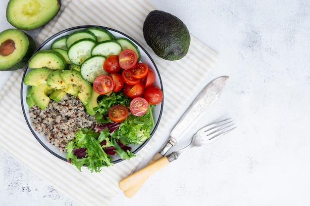 Gezond eten. budha kom met quinoa, avocado, komkommer, salade, tomaat, olijfolie.