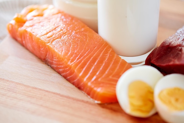 gezond eten, culinair, koken en dieet concept - close-up van zalmfilets, eieren en melk op houten tafel in de keuken