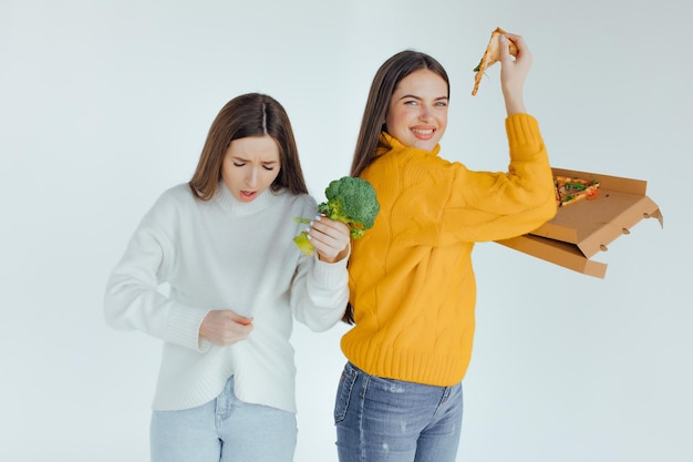 Gezond eten. De ene vrouw houdt een pizza vast en de andere een broccoli