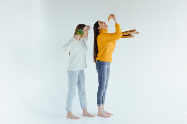 Gezond eten. De ene vrouw houdt een pizza vast en de andere een broccoli