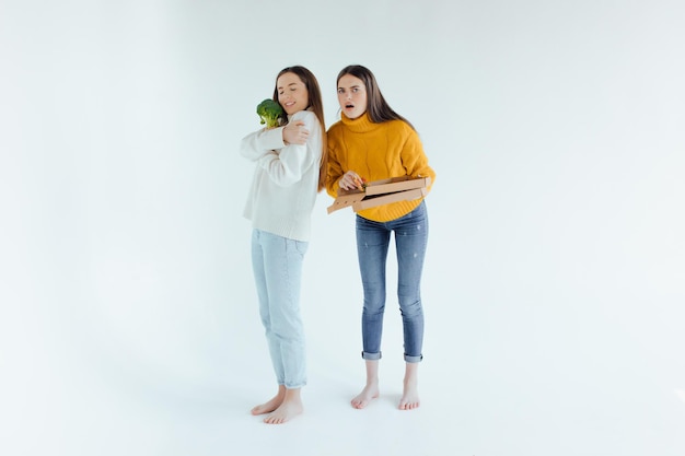 Gezond eten. De ene vrouw houdt een pizza vast en de andere een broccoli