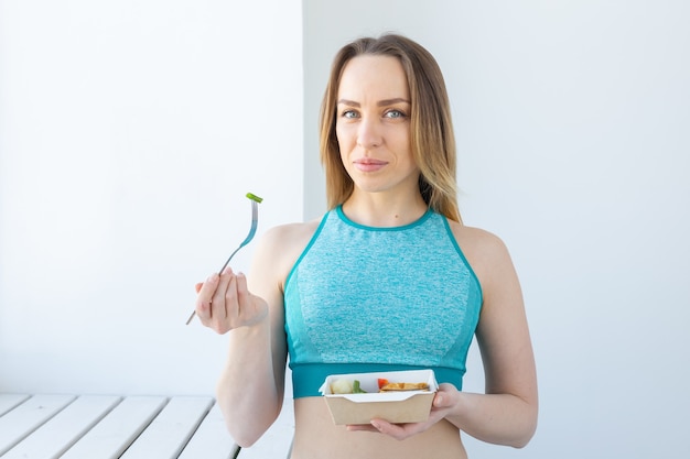 Gezond eten, diëten en fitness concept - jonge vrouw groente en vlees eten na training